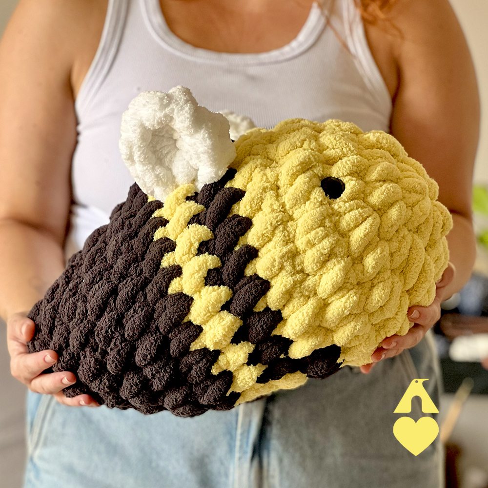 Abelha Giga Maxi Amigurumi finalizada no sofá, decorando sala de estar