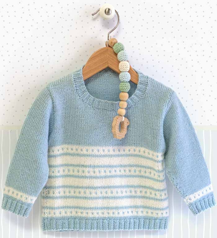 Pulôver de bebê listrado em tricô azul e branco pendurado em cabide de madeira, feito com Lã Baby Merino DMC
