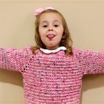 Sueter Infantil Picnic Croche Suéter Infantil Picnic de Crochê – criança com braços abertos, suéter rosa completo