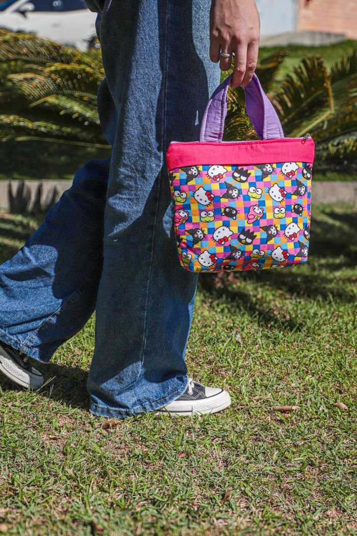 Pessoa caminhando ao ar livre segurando a Bolsa Hello Kitty de patchwork com tecido estampado colorido