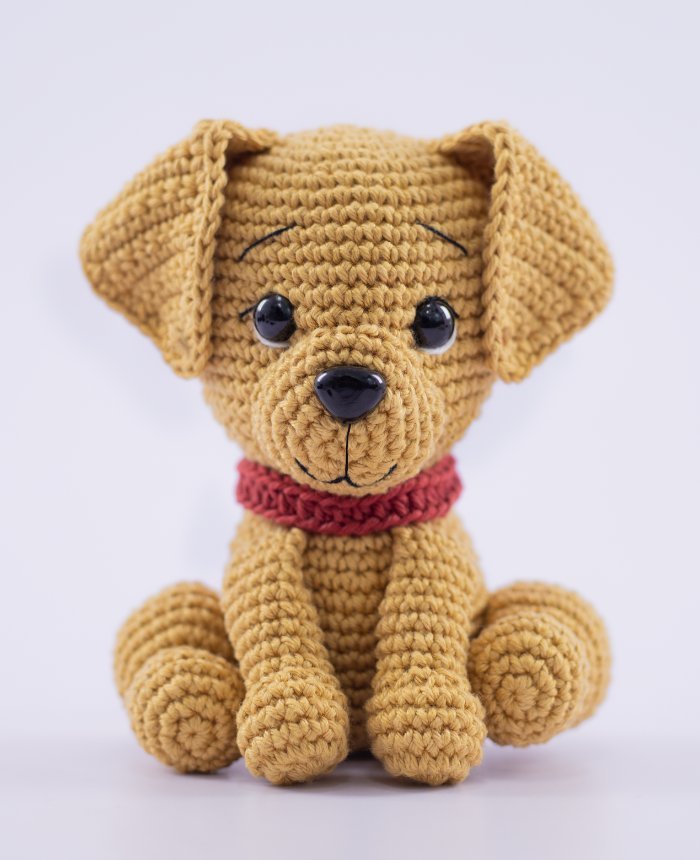 Cachorro Caramelo de Amigurumi em crochê — close-up frontal mostrando focinho, olhos de segurança e coleira rosa