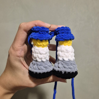 Pernas do Canarinho Pistola amigurumi montadas com shorts azul e chuteiras