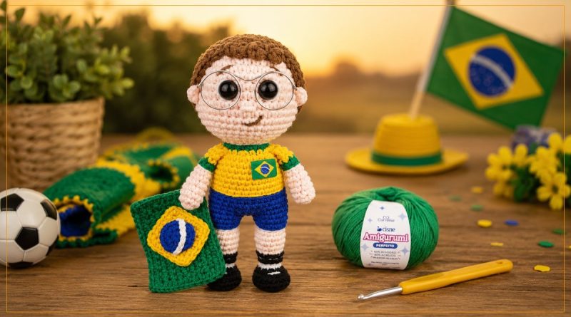 Amigurumi Garoto Torcedor do Brasil com camisa amarela, calção azul e óculos, segurando a bandeira, ao lado de novelo do Fio Cisne Amigurumi Perfeito verde