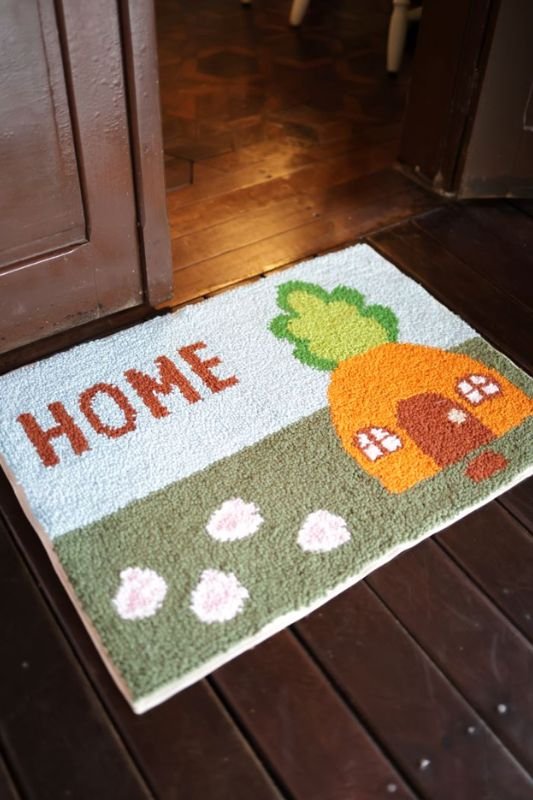 Tapete de Páscoa de Punch Needle posicionado na entrada de casa com design de casinha de cenoura