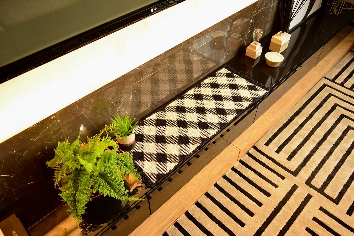 Trilho de mesa em crochê com padrão geométrico de losangos em preto e branco feito com técnica planned color pooling