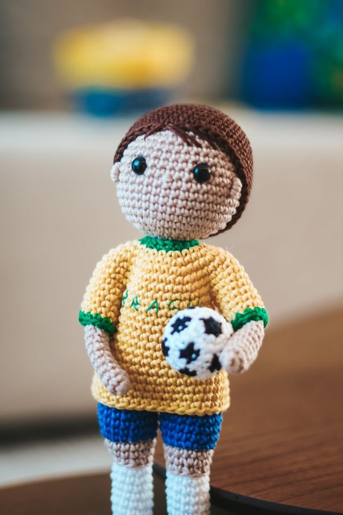 Amigurumi jogador de futebol segurando bola de crochê — técnica fio conduzido