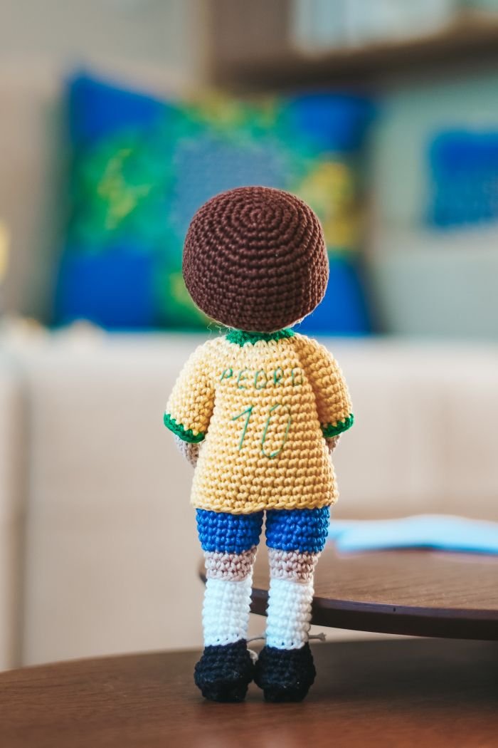 Detalhe da chuteira e pernas do amigurumi jogador de futebol — acabamento em preto com cadarço branco
