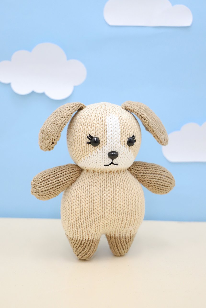 Cachorrinho Bartolomeu amigurumi de tricô circular, com corpo bege e detalhes caramelo, ao lado do novelo de Fio Amigurumi Círculo