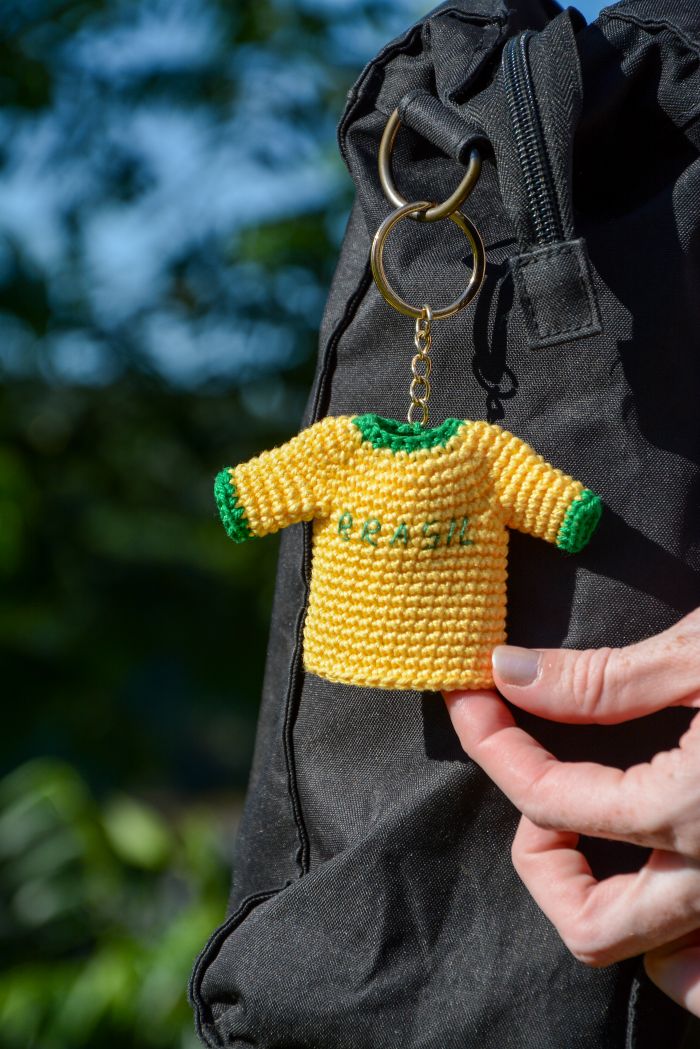 Chaveiro Camisa de Futebol de Crochê verde e amarelo com BRASIL bordado, pendurado em mochila preta