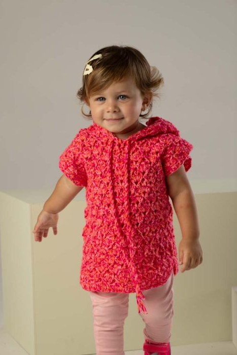 Colete de crochê infantil com capuz na cor framboesa, em ponto fantasia, vestido por uma menina