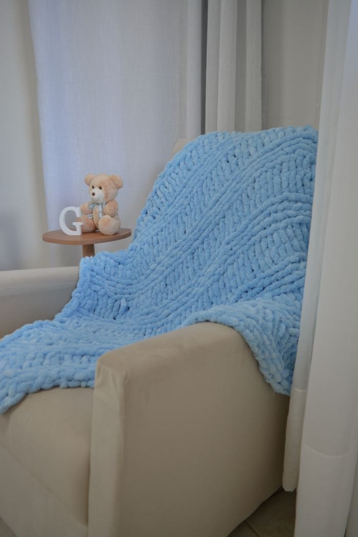 Manta Sky de tricô de mão na cor Azul Real feita com Fio Puffy Círculo sobre poltrona