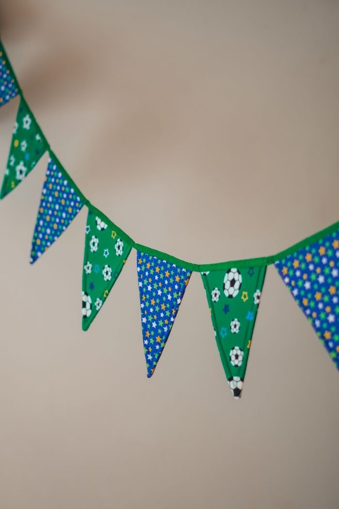 Detalhe das bandeirinhas da Copa em patchwork mostrando as estampas de bola de futebol e estrelas nos tecidos verde e azul