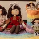 Boneca de pano Maria com sorvete e outras bonecas em cesto de crochê sobre tapete arco-íris
