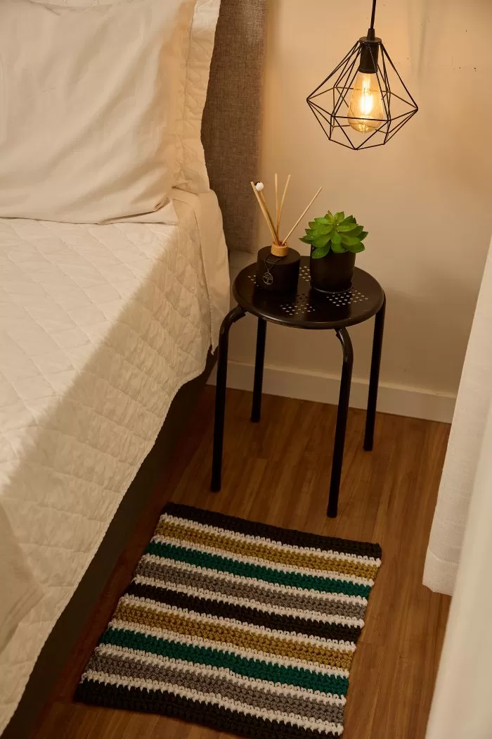 Tapete Figo de crochê com listras coloridas feito com Fio Náutico Círculo ao lado da cama