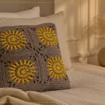 Almofada Solar de Crochê com Barbante Barroco Maxcolor — quatro motivos sol em cinza e amarelo