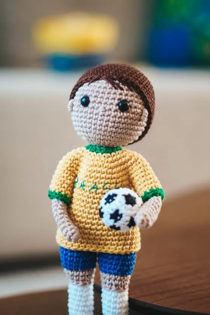 Amigurumi jogador de futebol segurando bola de crochê — técnica fio conduzido