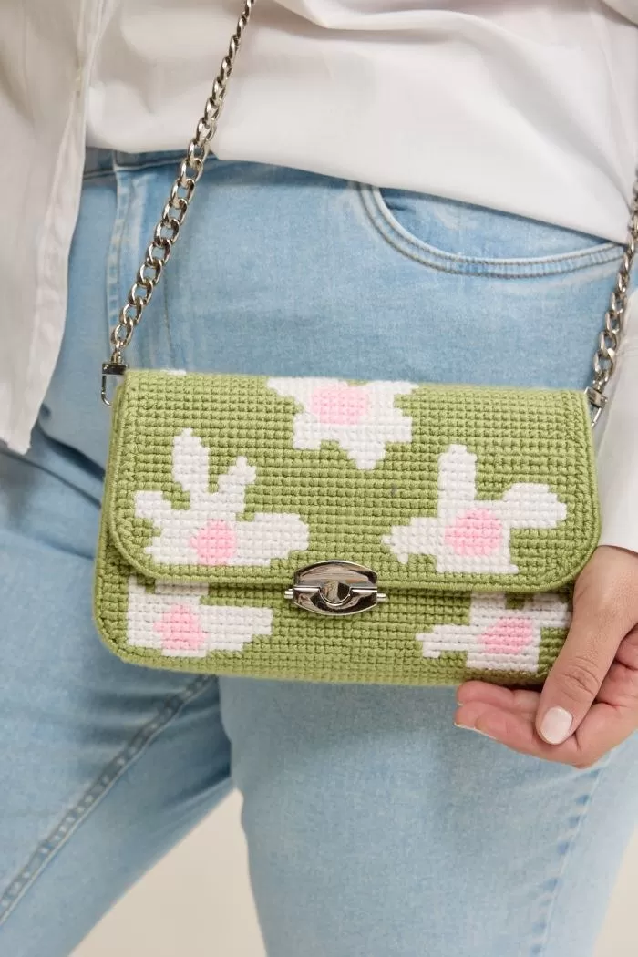 Bolsa Daisy bordada em ponto cruz com margaridas brancas e miolo rosa sobre fundo verde pistache