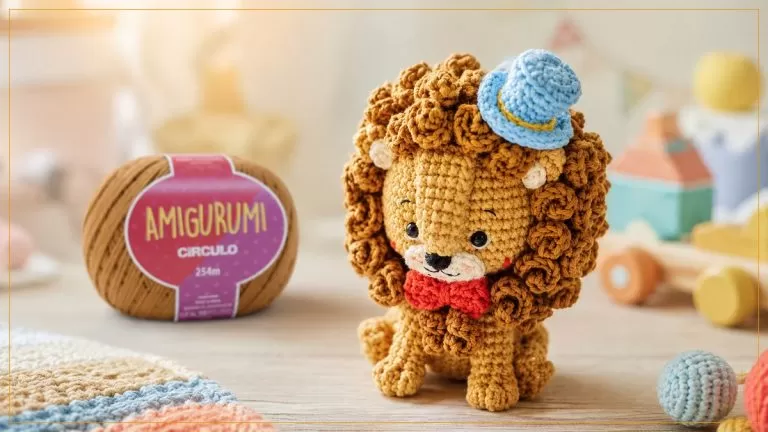 Amigurumi de leão de crochê com chapéu azul, ao lado do novelo Fio Amigurumi Círculo