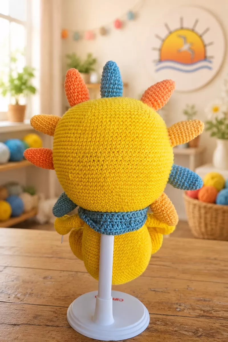 Vista de trás do Solzinho de amigurumi, mostrando os raios e o lenço azul